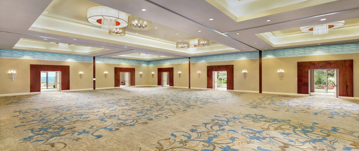 The Shearwater Ballroom at Cape Rey Carlsbad Beach, empty, with patterned carpet and chandeliers