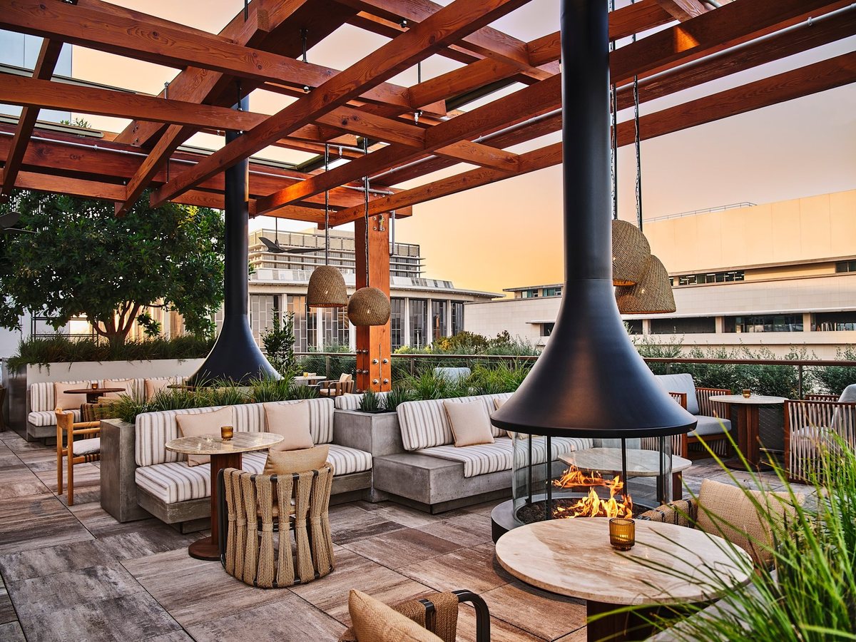 Alto, the rooftop at Conrad Los Angeles, with a hanging fireplace, lounge seating and a sunset view