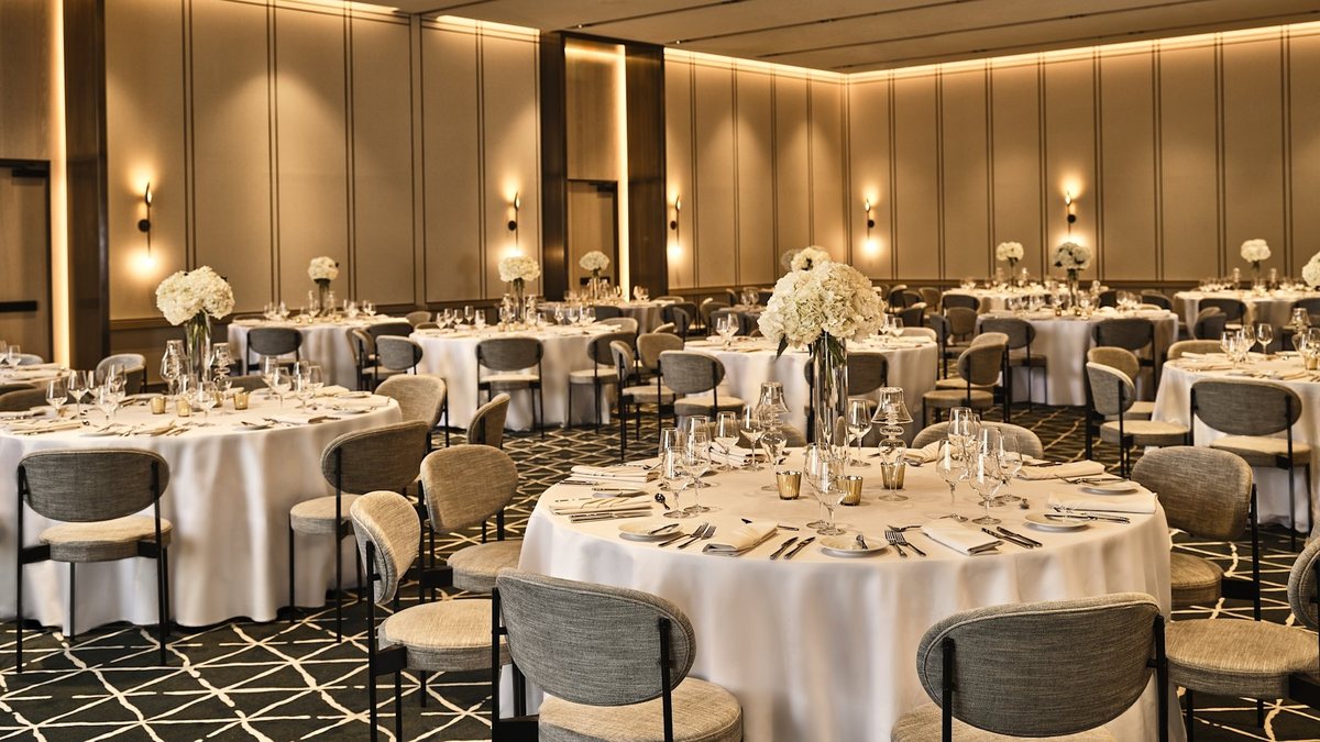 The Grand Park Ballroom at Conrad Los Angeles set with round tables under warm wall lighting