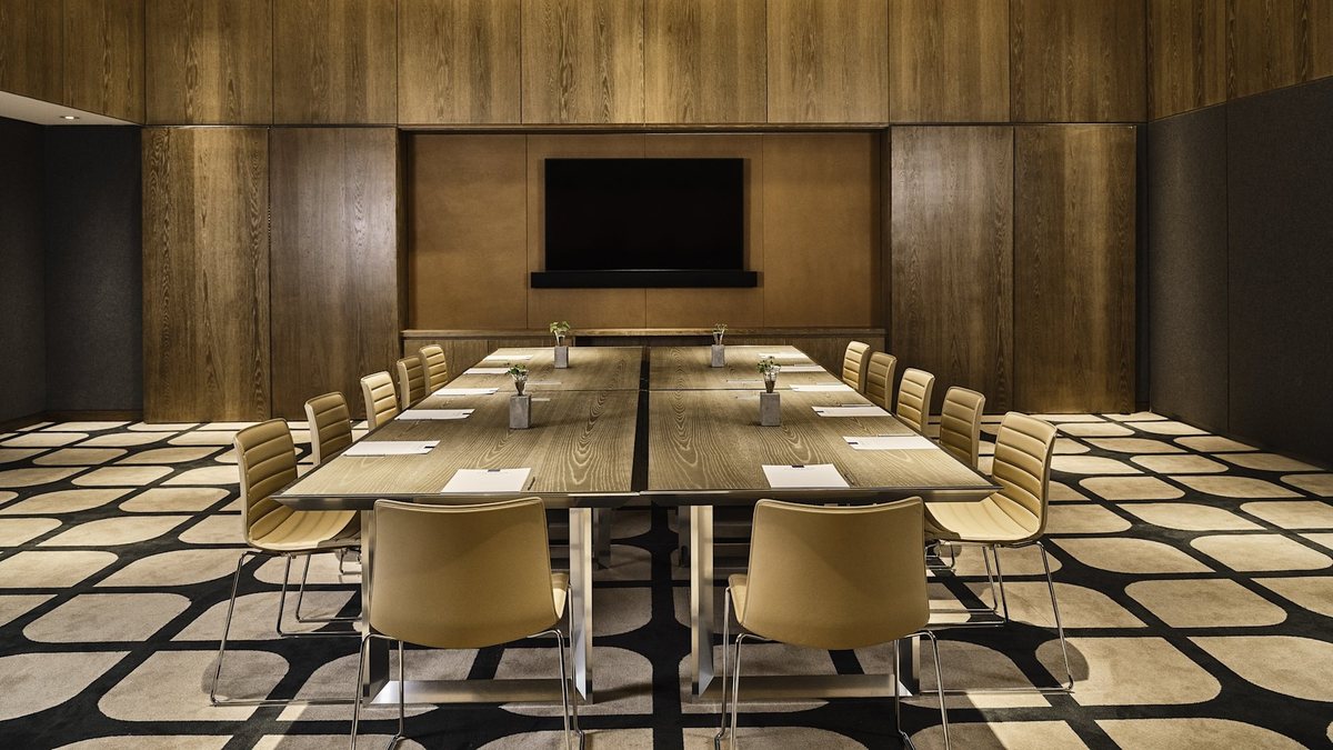 Olive at Conrad Los Angeles set conference style with a wall-mounted TV and wood paneling