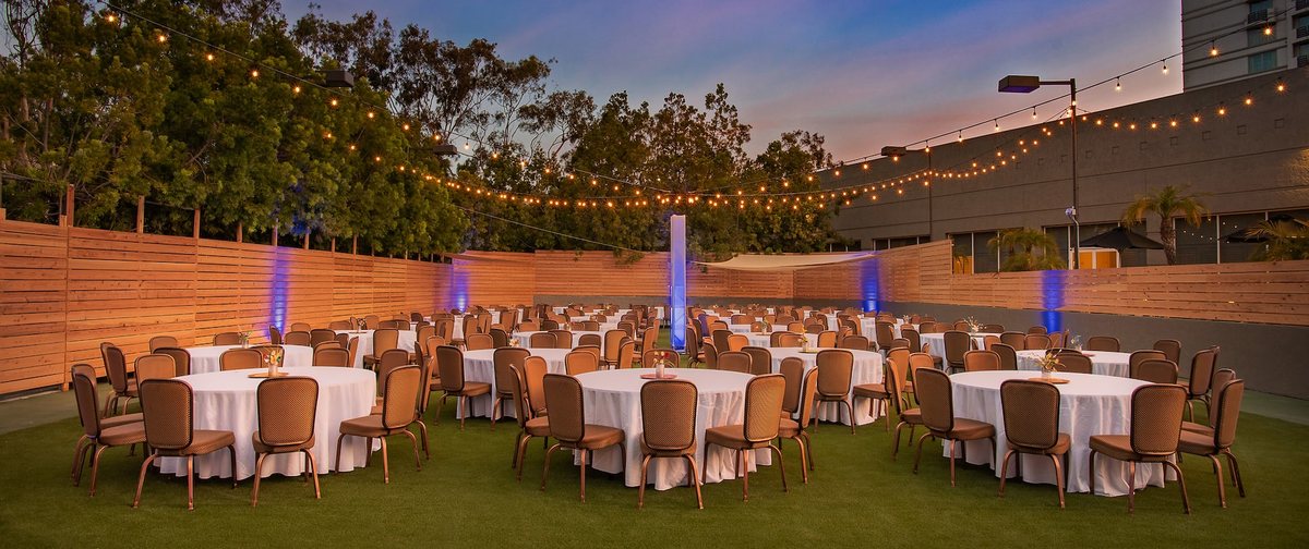 The Patio at DoubleTree San Diego Mission Valley at dusk with round tables and string lights