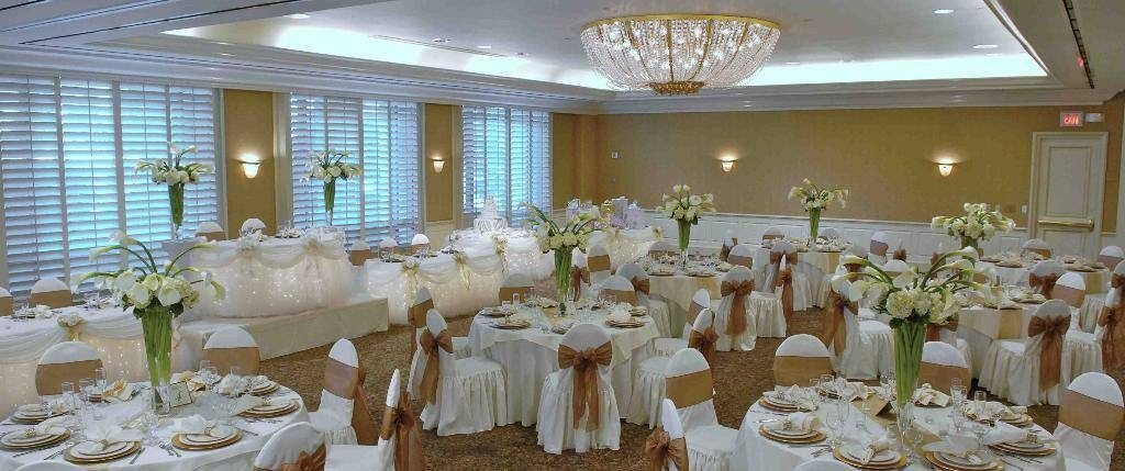 The Crystal Ballroom at DoubleTree Torrance set for a wedding with round tables, white chair covers and a chandelier