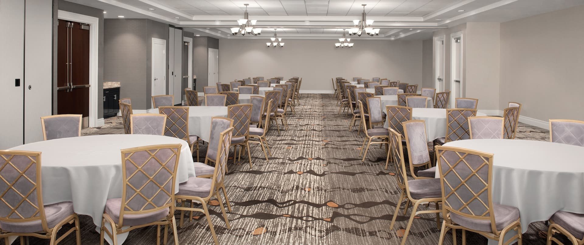 A meeting room at Embassy Suites La Quinta set with round tables under chandeliers