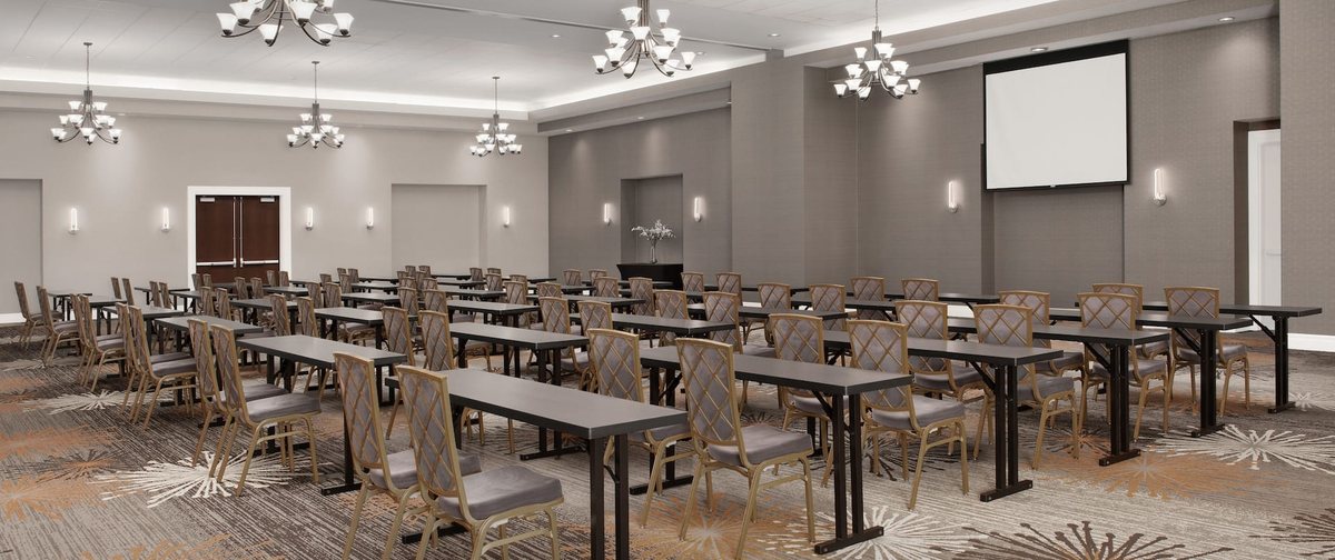 The Santa Rosa room at Embassy Suites La Quinta set classroom style with chandeliers and a screen