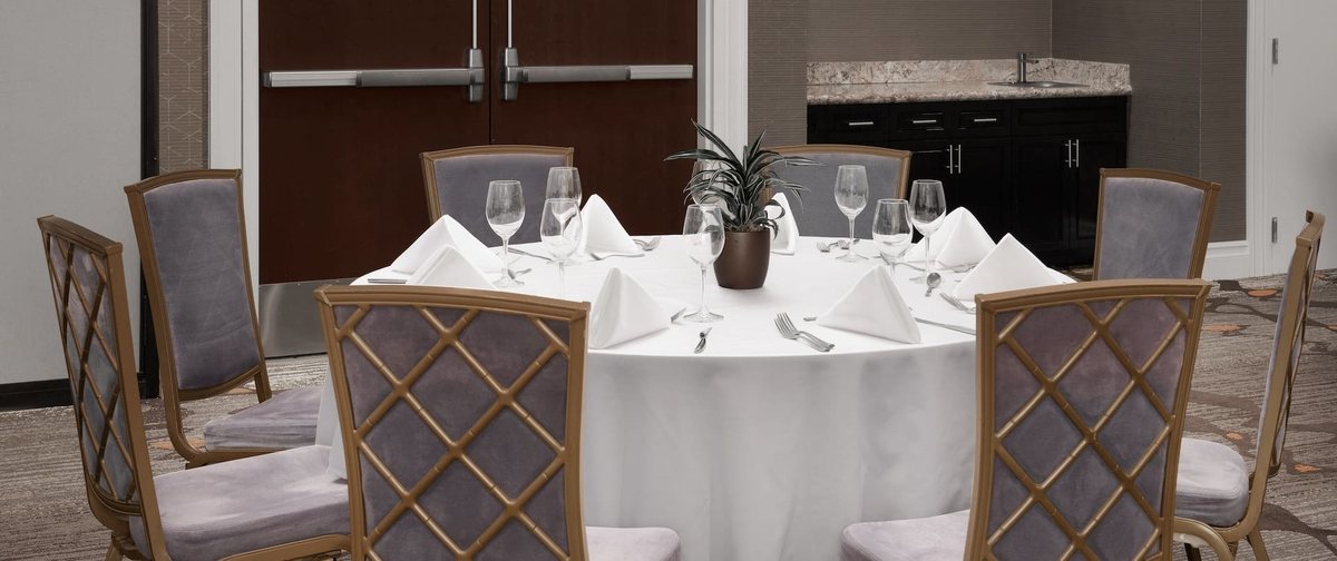 A round banquet table set with white linen and glassware in the Santa Rosa Ballroom at Embassy Suites La Quinta
