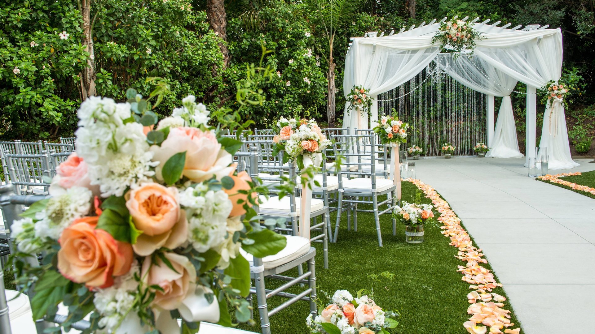 Outdoor wedding ceremony site at Fullerton Marriott with a white arch, flowers and garden seating