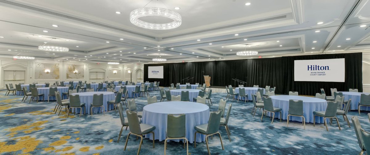 The Crystal Ballroom at Hilton Irvine/Orange County Airport with round tables and projection screens