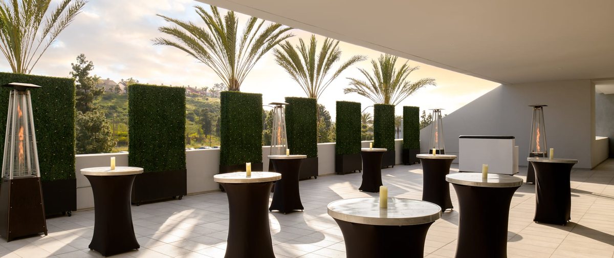 The outdoor terrace at Hilton Los Angeles Culver City set with standing cocktail tables