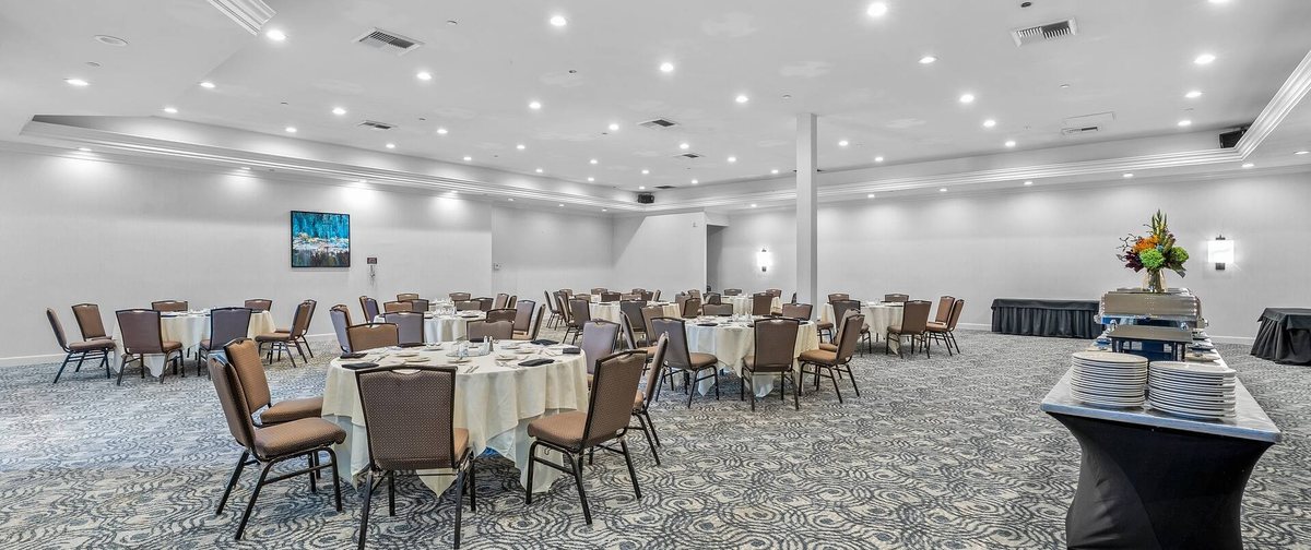 The Derby Room at Hilton San Diego/Del Mar with round tables and chairs and a buffet table