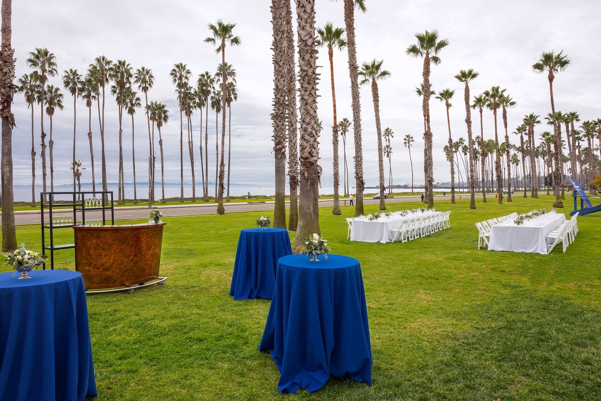 The Front Lawn at Hilton Santa Barbara Beachfront Resort set with cocktail tables under palm trees
