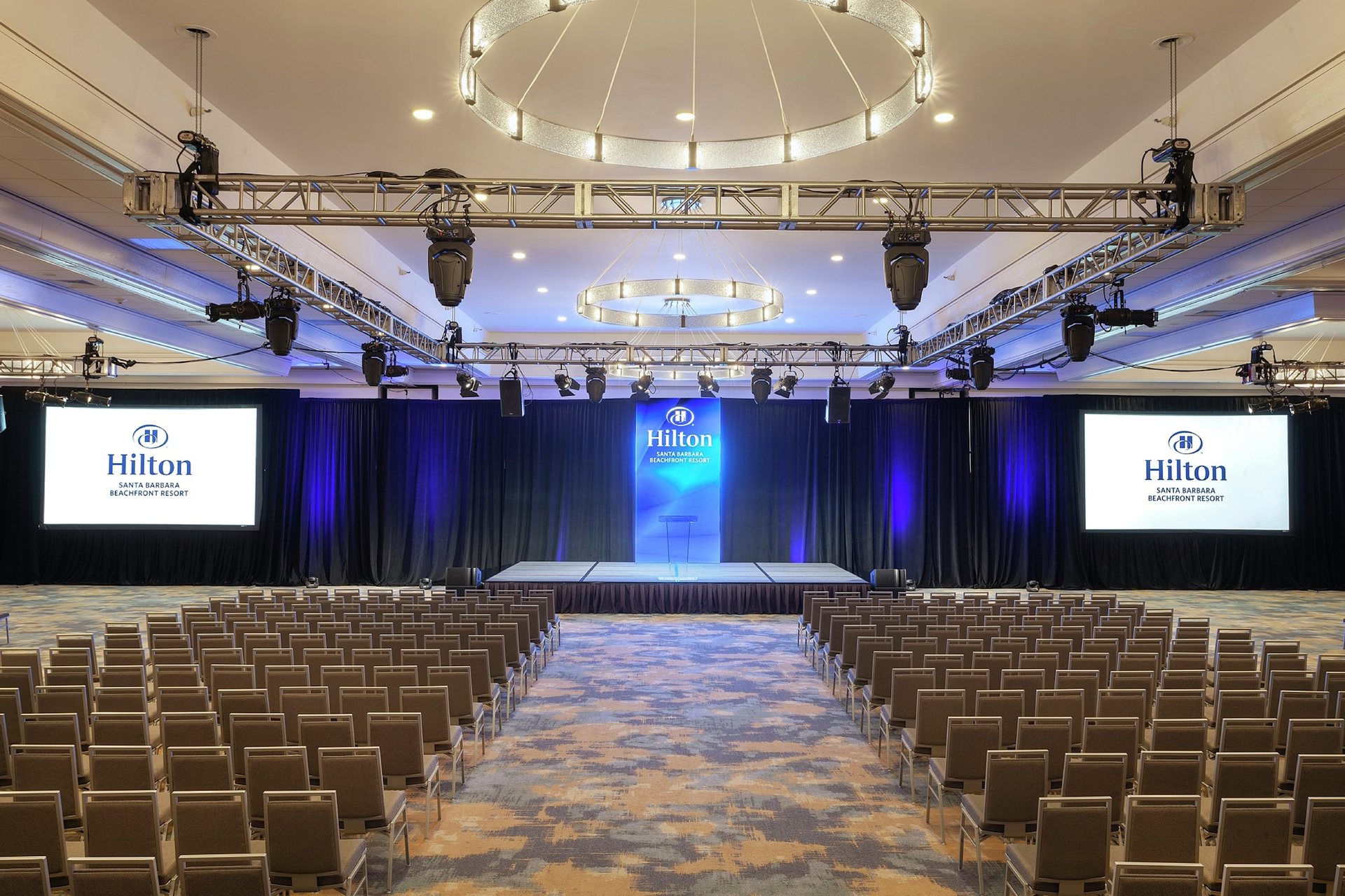 The Grand Ballroom at Hilton Santa Barbara Beachfront Resort set theater style facing a stage with three screens