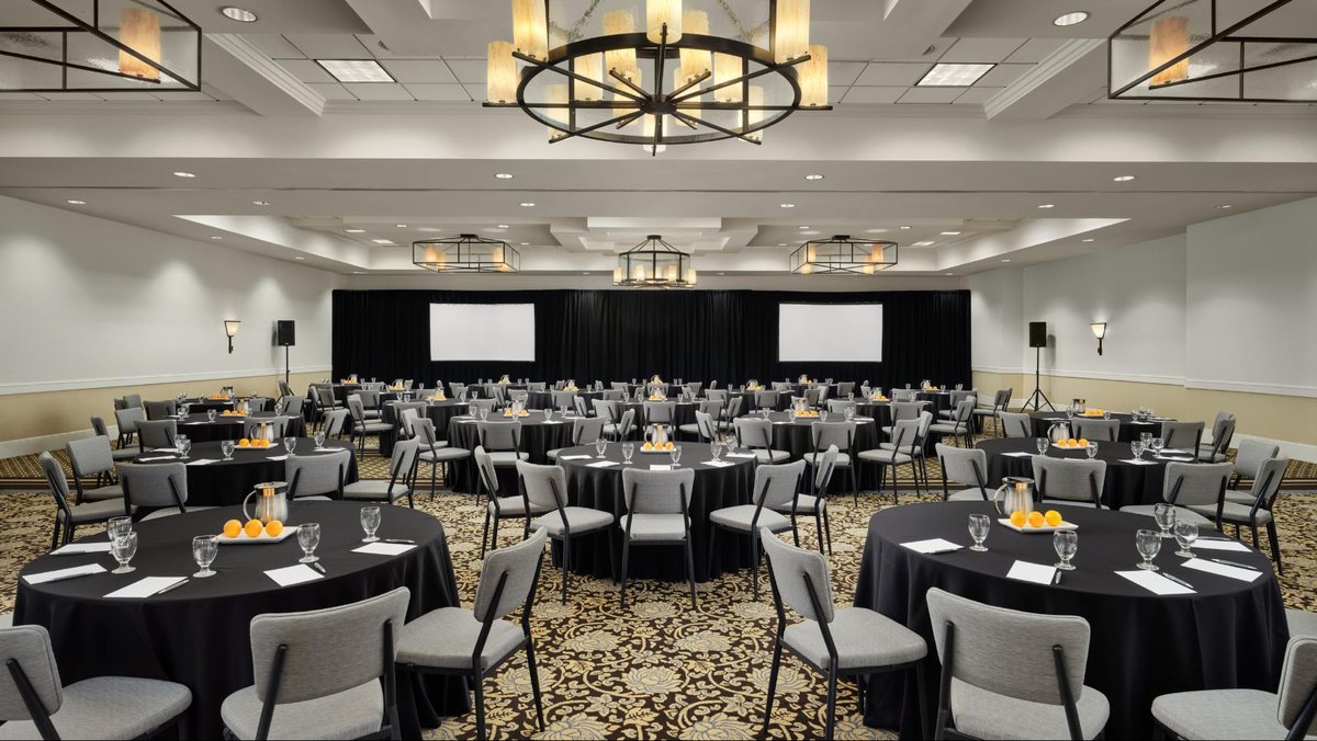 The Sunset Ballroom at Hotel Solea set with round tables facing a stage and screens