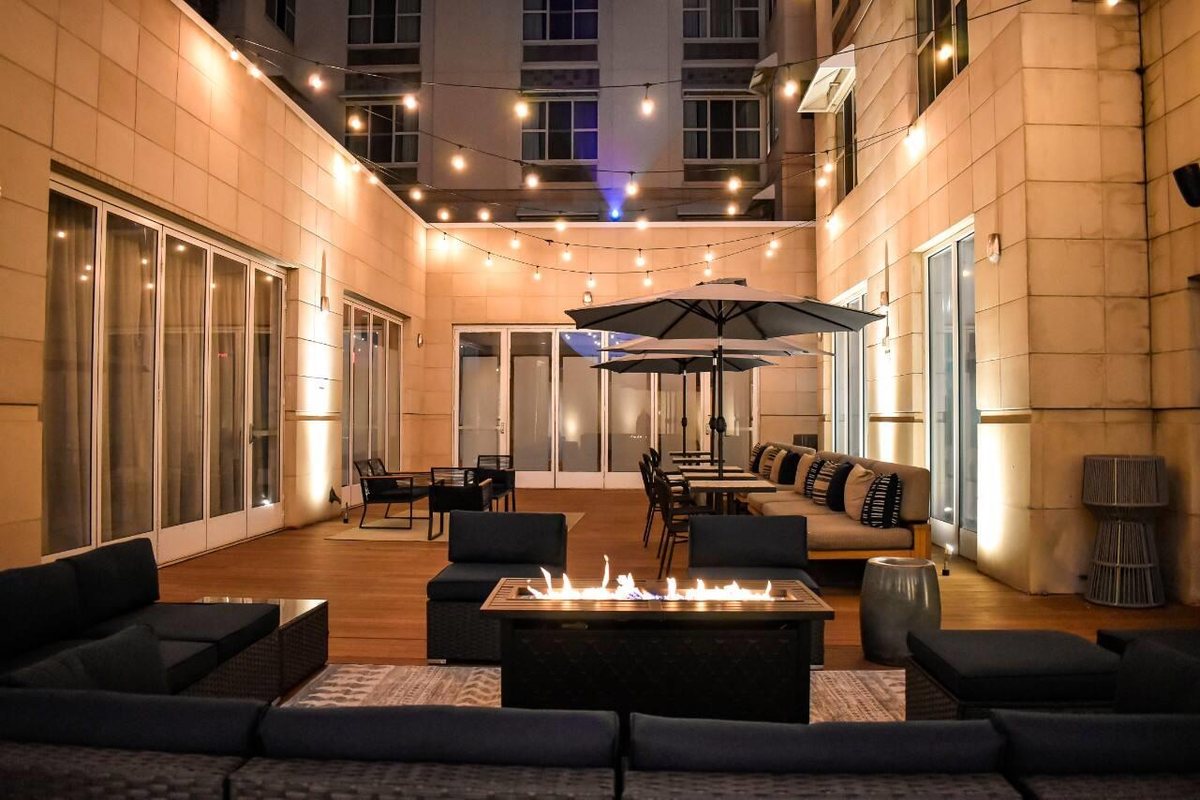 The courtyard at Hyatt Centric The Pike Long Beach with lounge seating and a fire feature at night