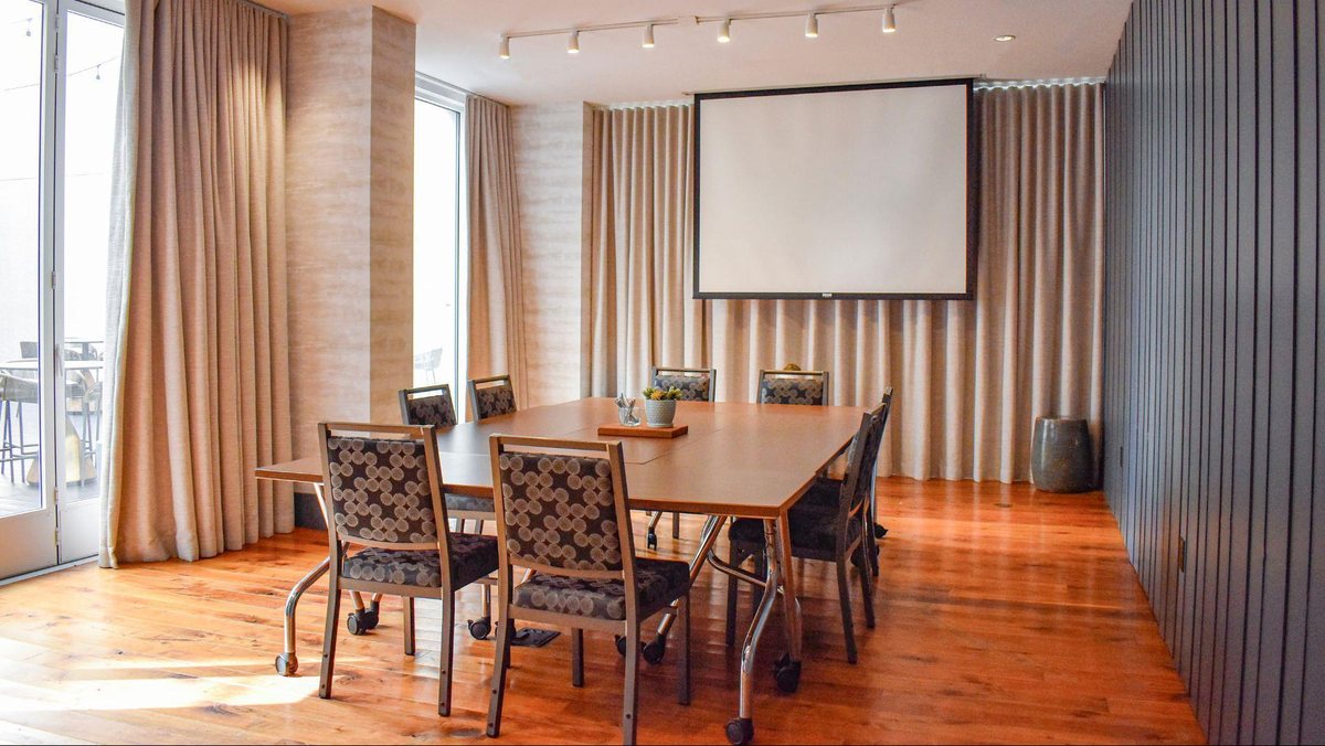 The Gateway room at Hyatt Centric The Pike Long Beach set conference-style facing a projection screen