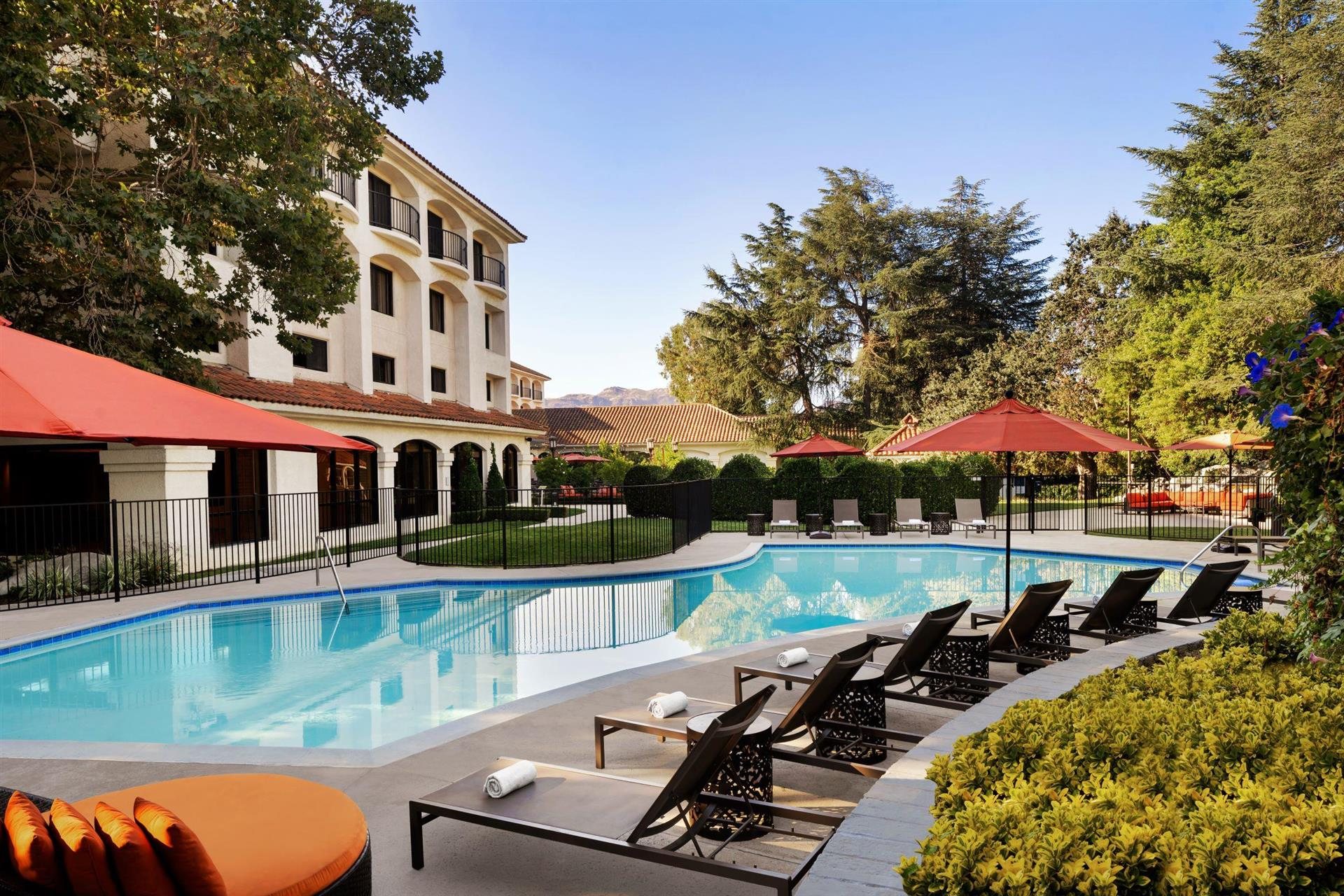 The Waterfall Pool at Hyatt Regency Westlake with red umbrellas and lounge chairs