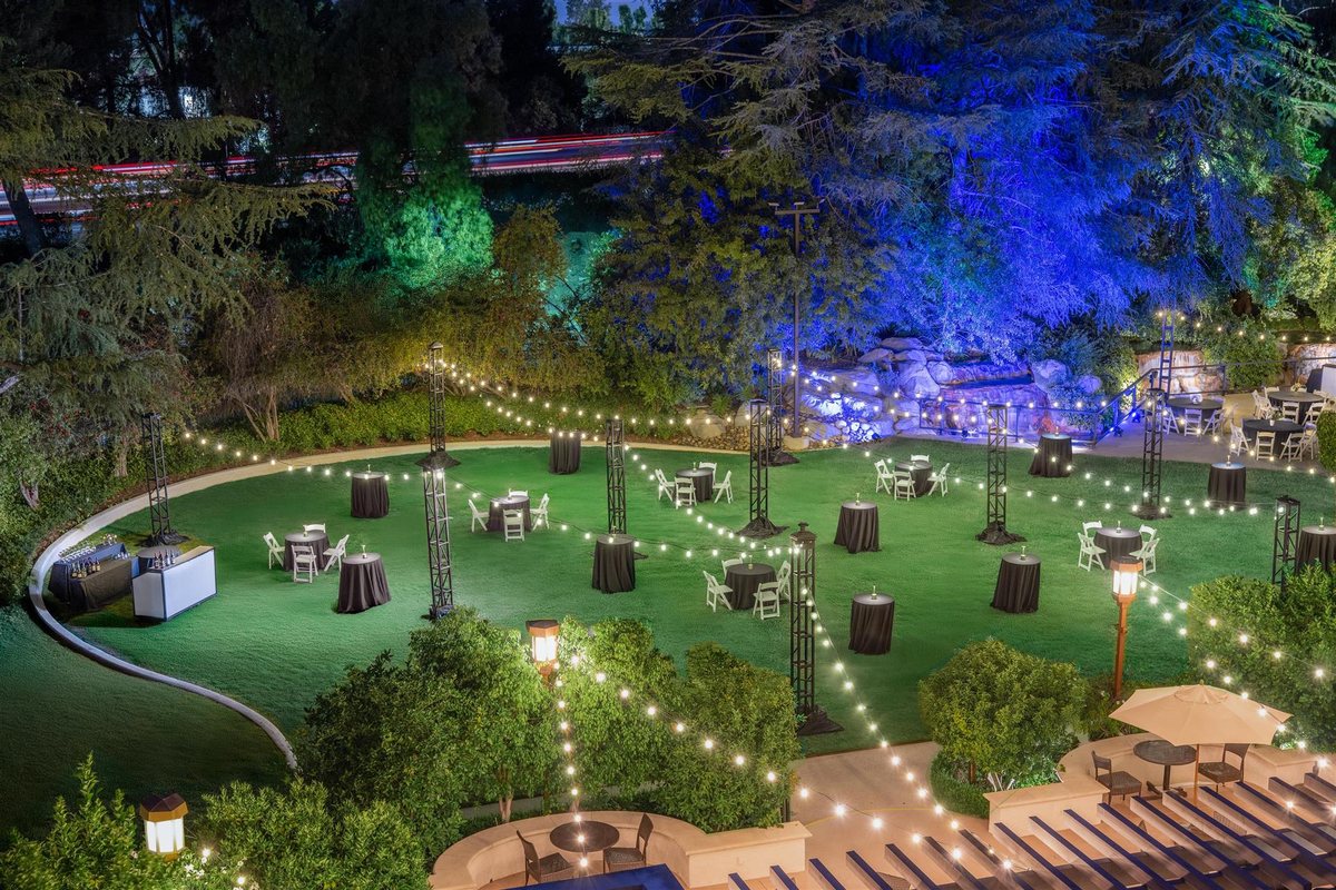 The Grand Lawn at Hyatt Regency Westlake at night with lit trees and a stage