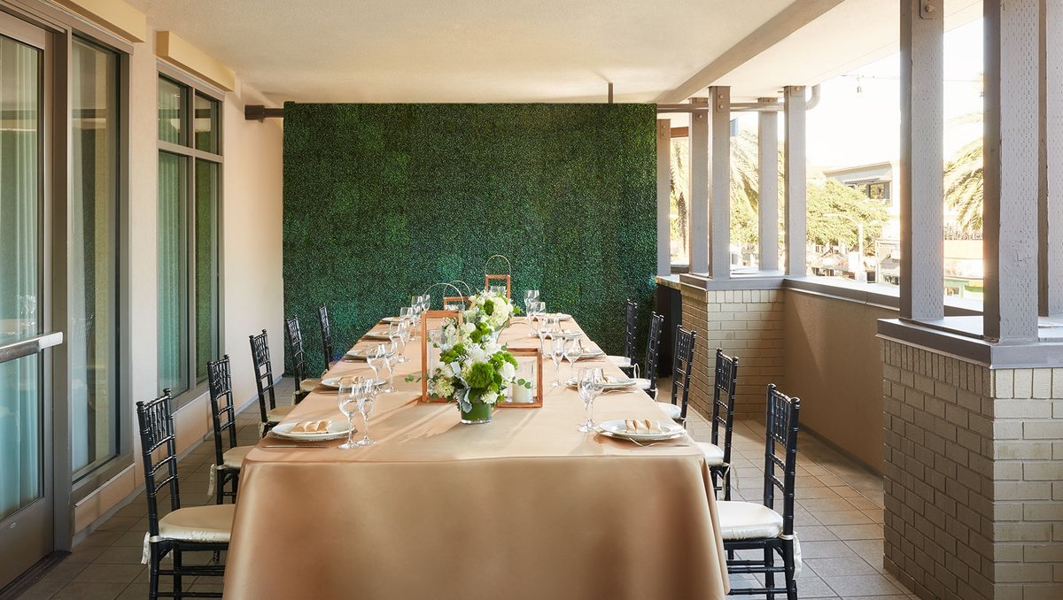 A long dinner table set on a covered terrace at Kimpton Shorebreak