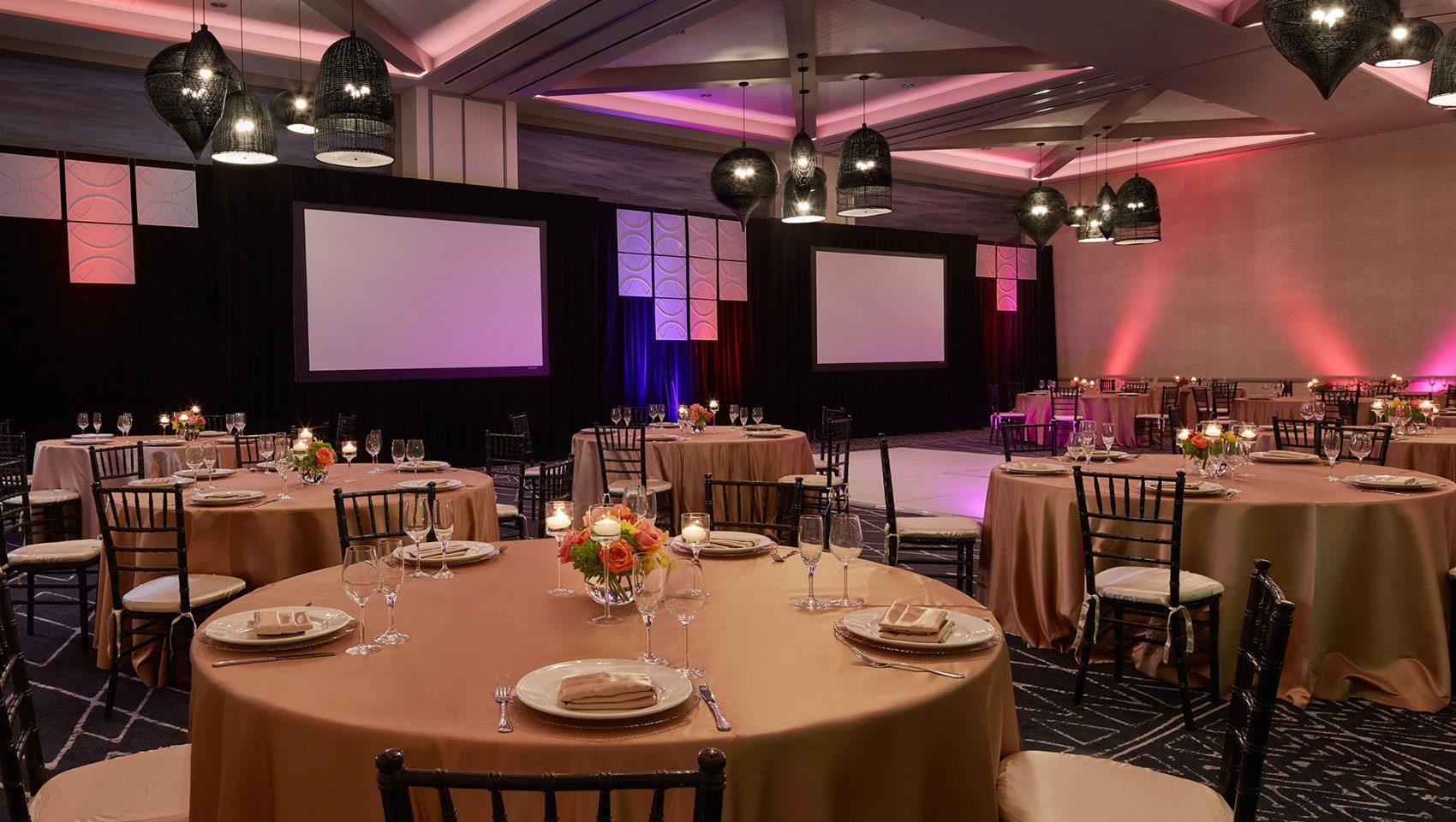 The Epic Ballroom at Kimpton Shorebreak set for a social event with round tables and colored uplighting