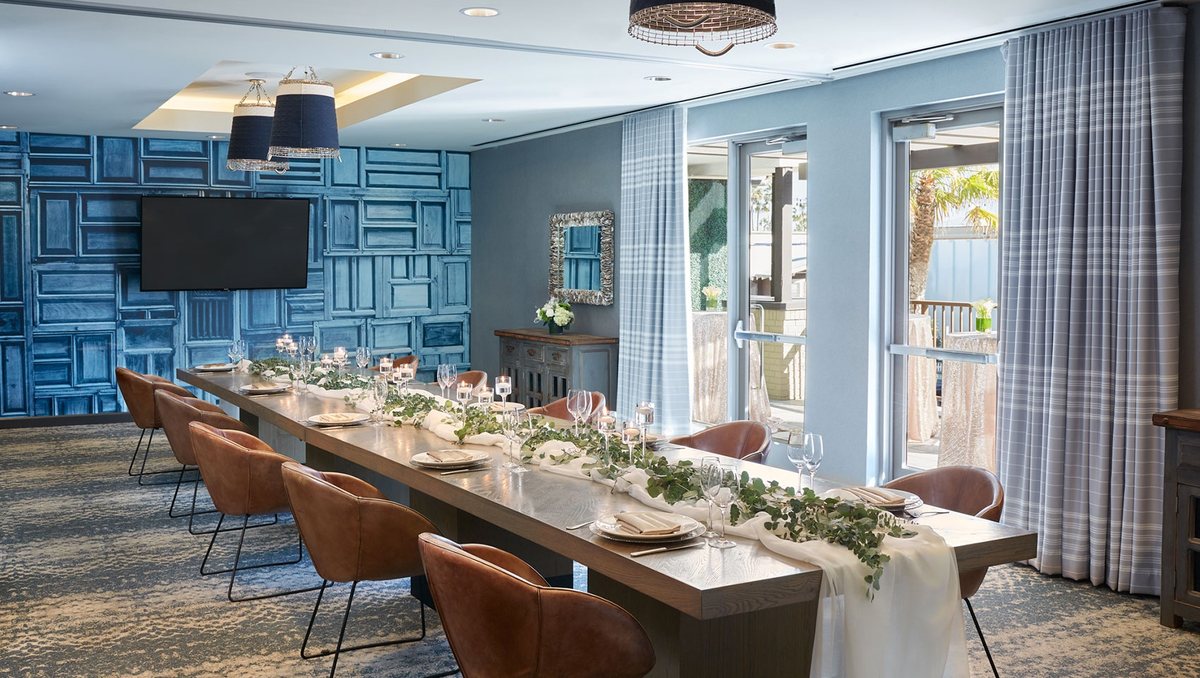 South Swell at Kimpton Shorebreak set for a dinner at a long table with a wall-mounted TV