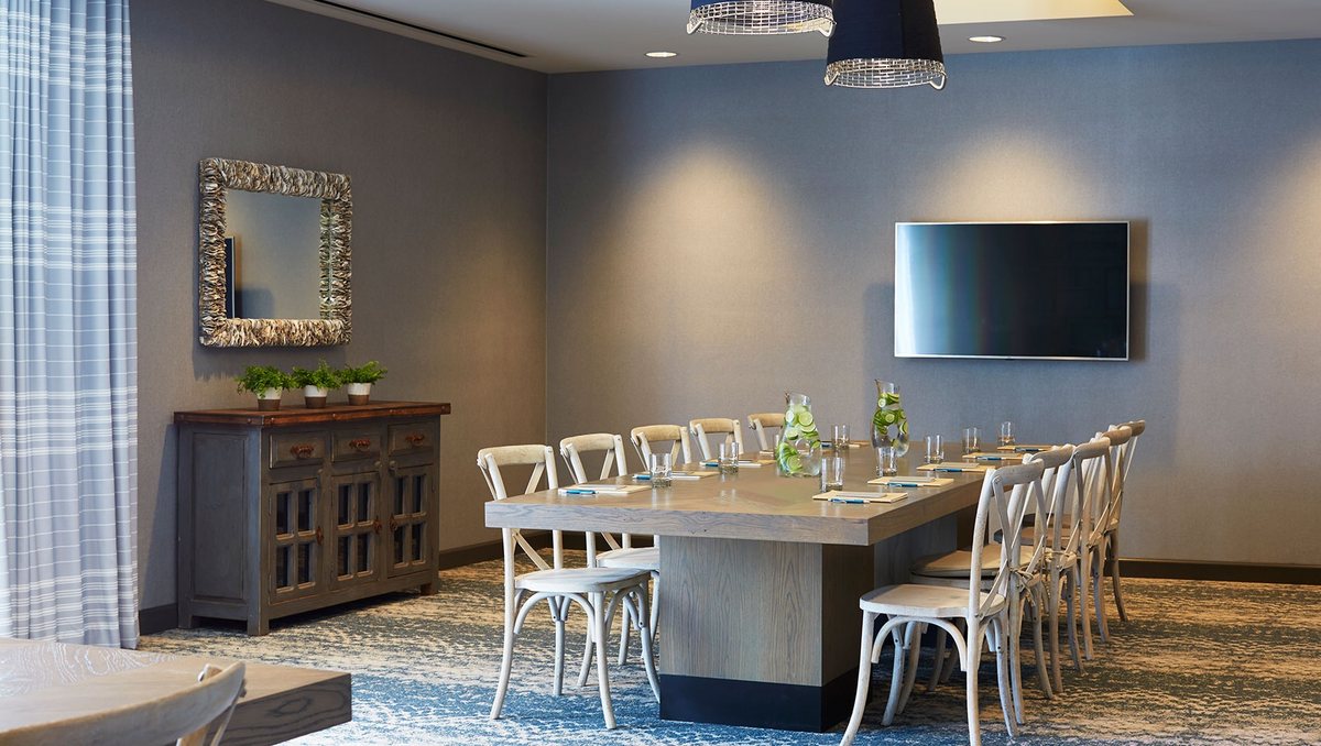 A small meeting room at Kimpton Shorebreak set conference style with a wall-mounted display