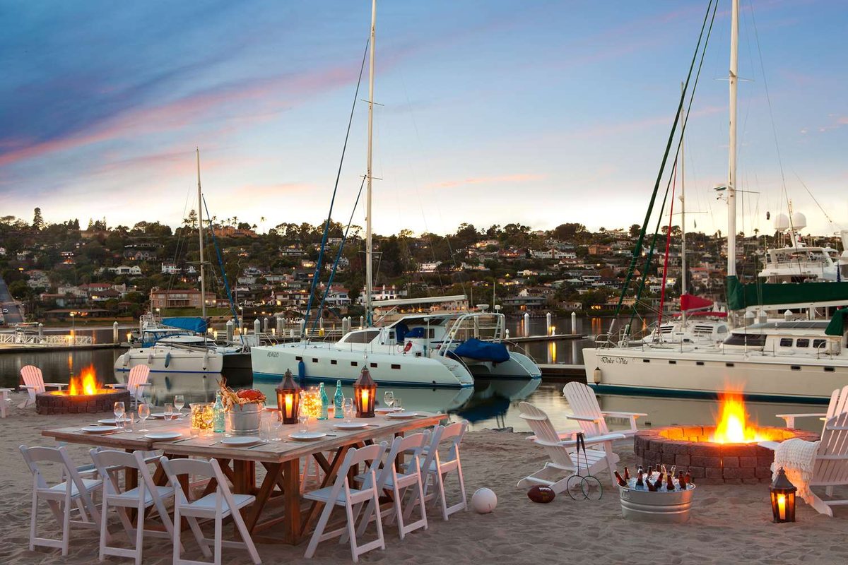 A beach reception at Kona Kai San Diego Resort with lounge seating and a fire pit by the marina