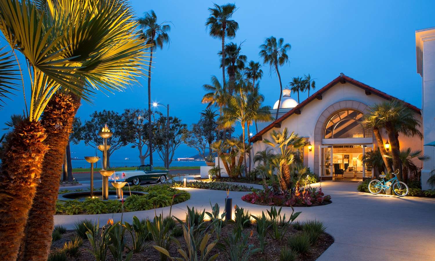 Kona Kai San Diego Resort at dusk with palm trees and its lit entrance