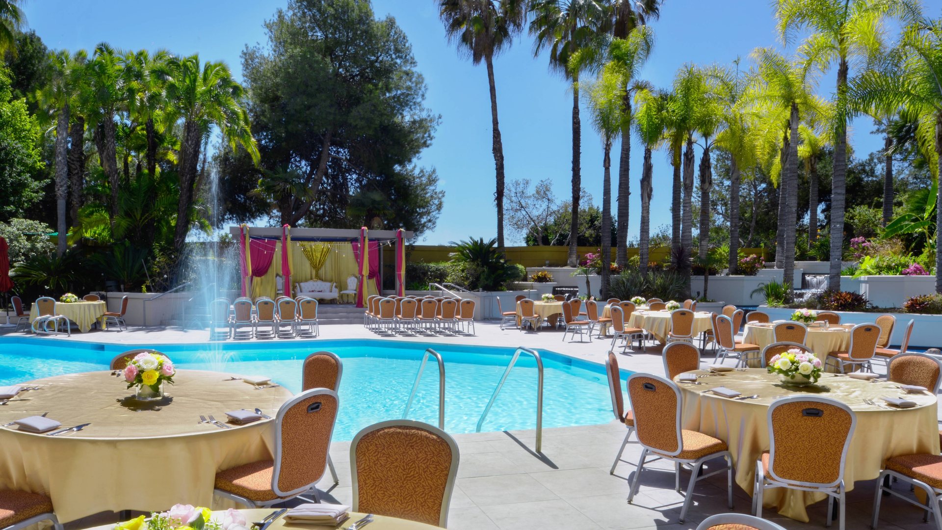 Outdoor pool wedding at Long Beach Marriott with tables set beside the pool under palm trees