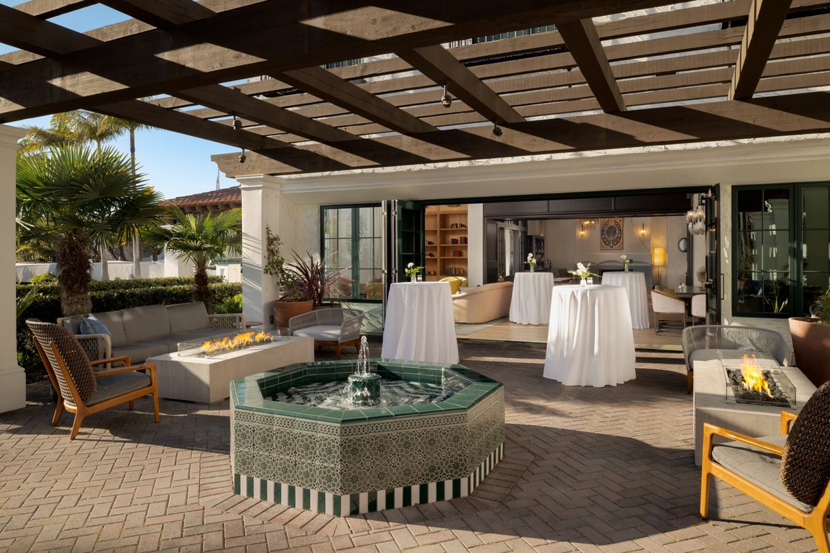 The Oceanfront Terrace at Mar Monte Hotel with a tiled fountain, pergola and cocktail tables