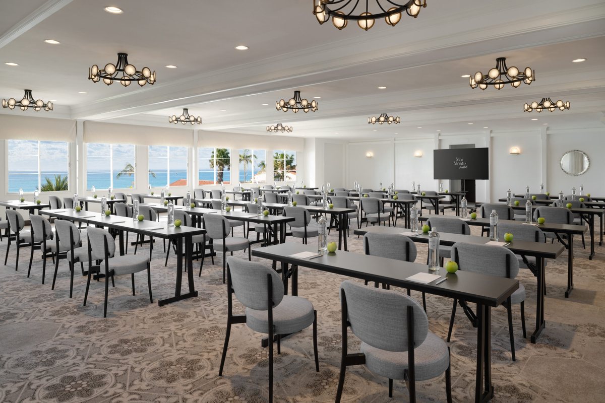 The Pacific Ballroom at Mar Monte Hotel set classroom style under chandeliers, with a screen at the front