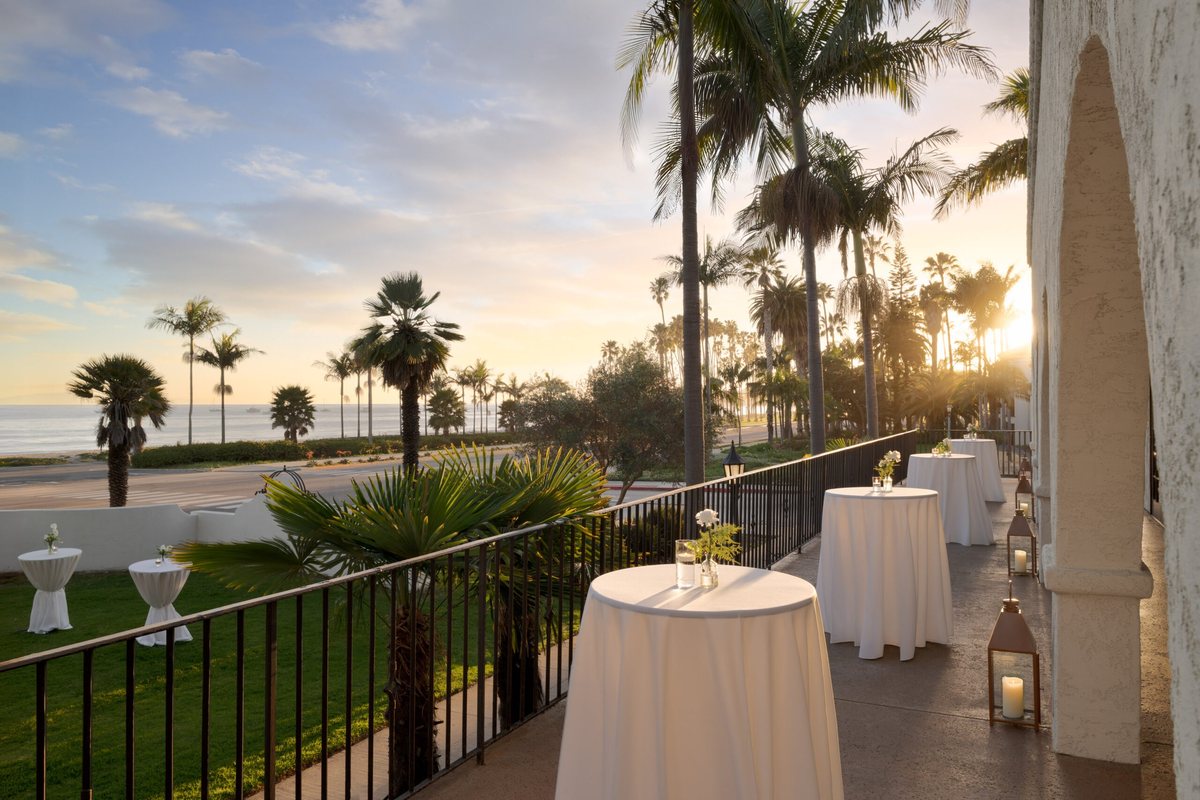 The Terrace Patio at Mar Monte Hotel at sunset with cocktail tables, palms and ocean views