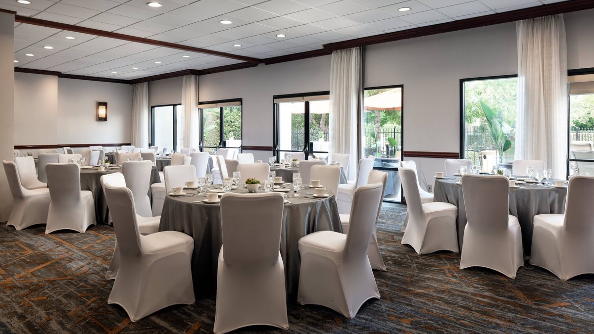 The Regency Ballroom at Marriott Riverside set for a banquet with white chair covers and large windows