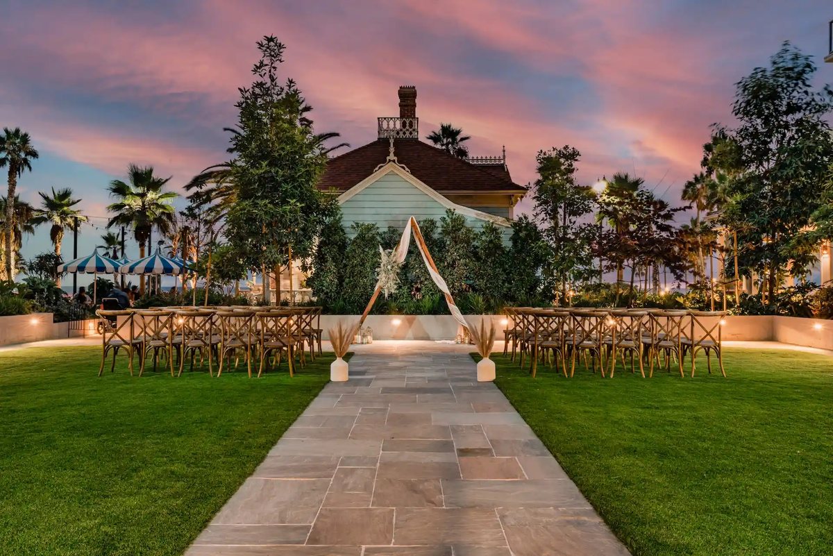 The Pacific Garden lawn at Mission Pacific Beach Resort set for a ceremony at sunset, with the Top Gun House behind