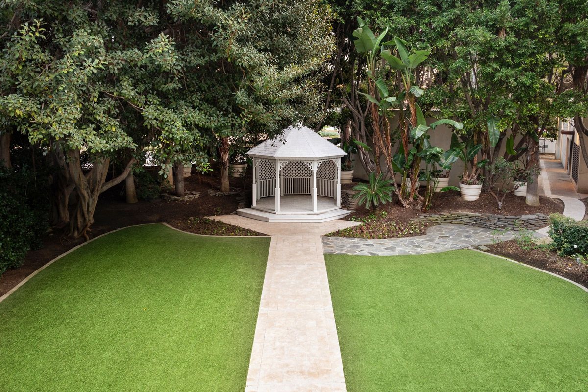 The Garden Gazebo at Renaissance Newport Beach Hotel with a white gazebo on a lawn among trees