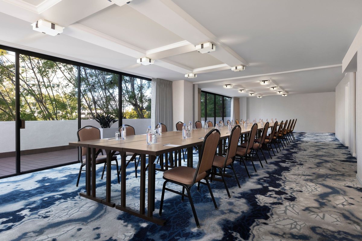 The Torrey Pine room at Renaissance Newport Beach Hotel with a long table and windows onto trees