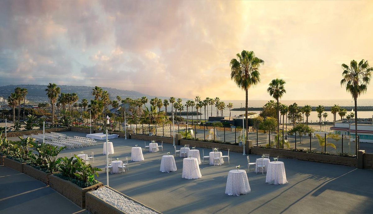 The Harbor Terrace at Sonesta Redondo Beach & Marina at sunset with palm trees and the marina beyond