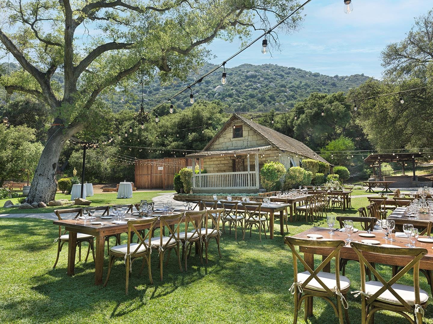 The Stone House Dining Lawn at Temecula Creek Inn set with long tables under oak trees