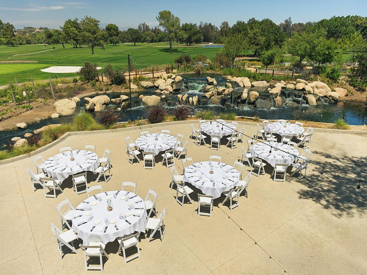 The Plaza at Temecula Creek Inn set with round tables beside the golf course and waterfall
