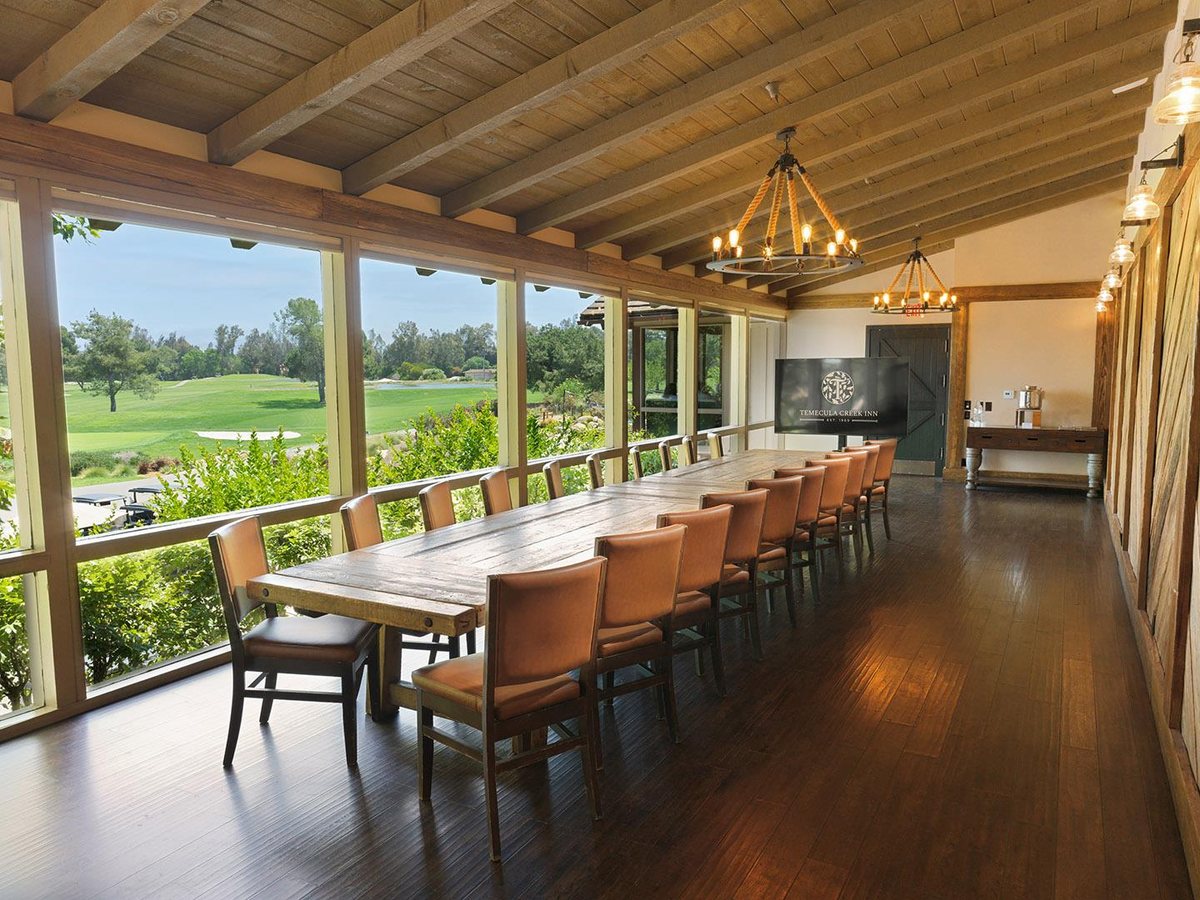 The Quarry Room at Temecula Creek Inn with a long dining table and a wall of windows facing the golf course