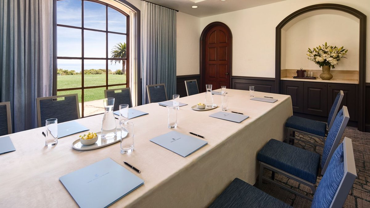 A boardroom with a long table and windows onto the grounds