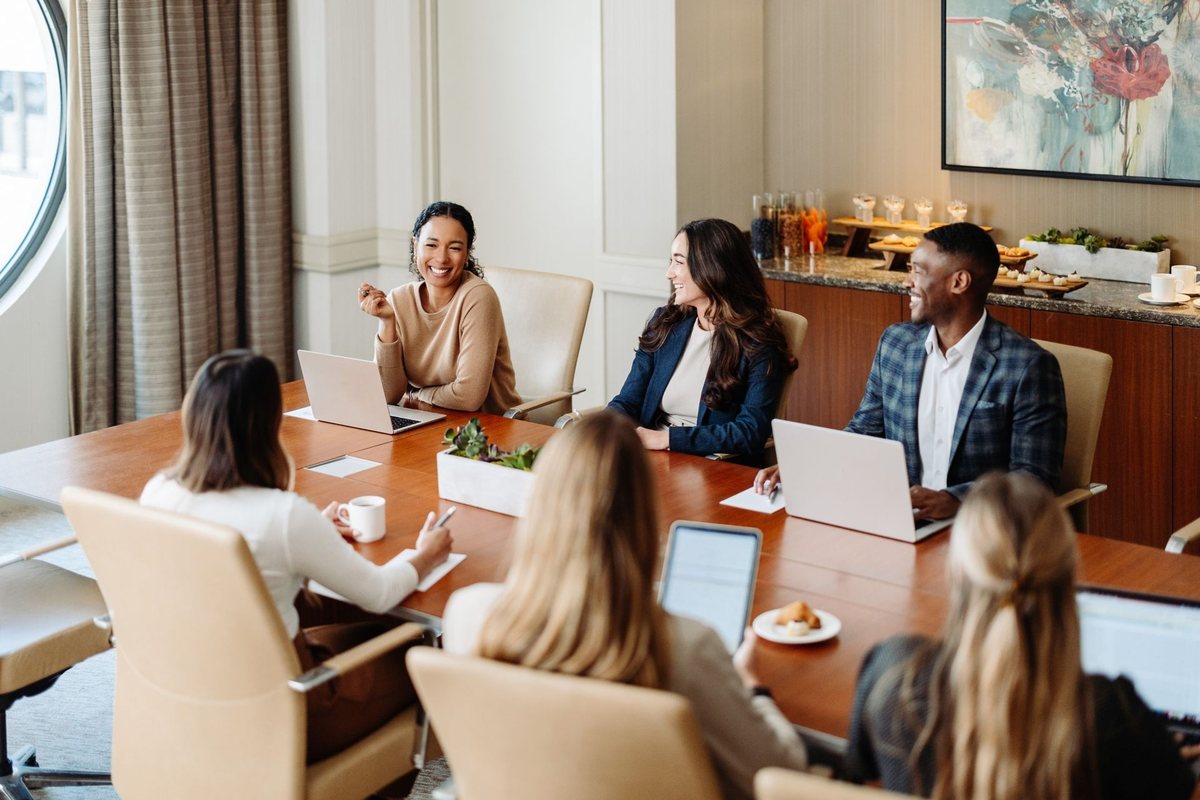 A small group meeting around a boardroom table by large windows