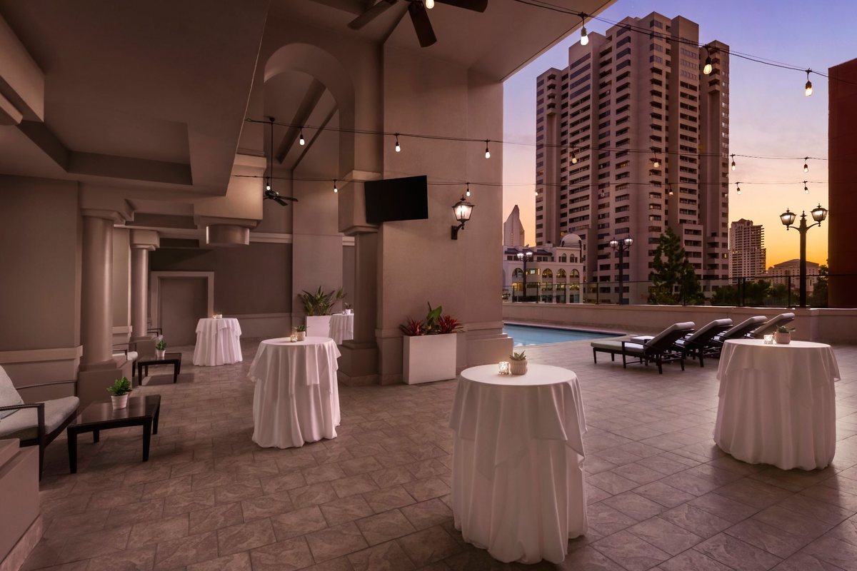 A rooftop pool reception with cocktail tables at dusk