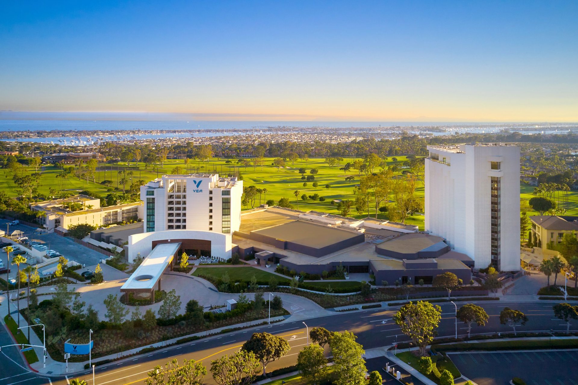 Aerial view of VEA Newport Beach with the golf course and the coastline behind