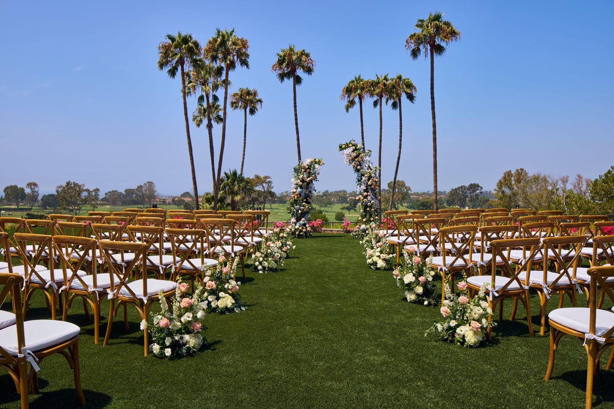 Marea Lawn set for an outdoor ceremony with rows of chairs under palm trees