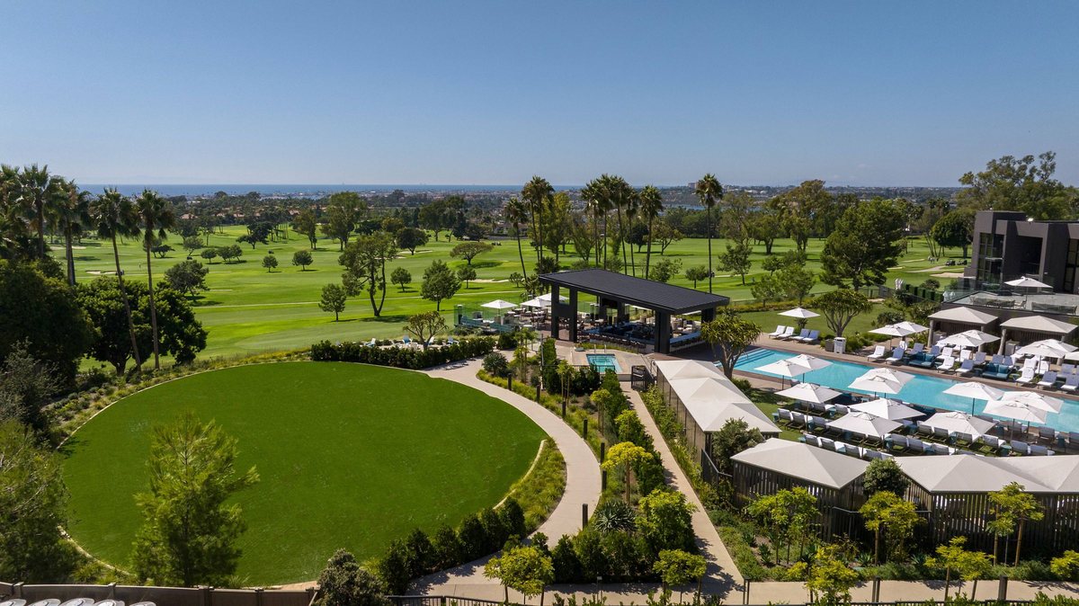 Aerial view of the oval Sunset Lawn with the golf course and coastline beyond