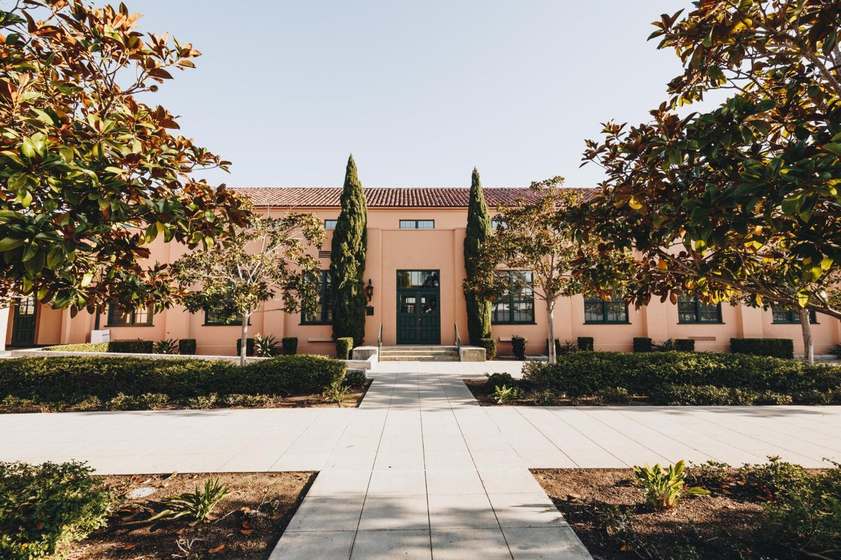 The brick Vesper Venue building at the end of a landscaped walkway between two large trees