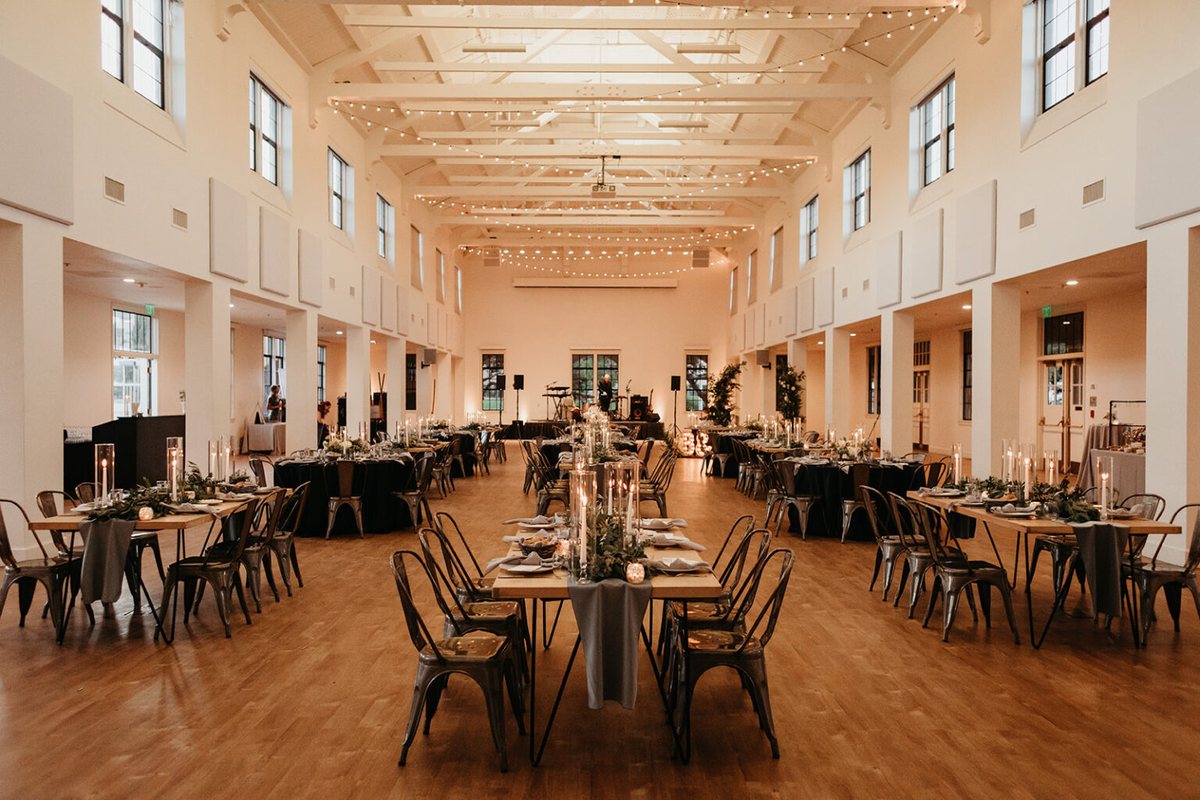 Long reception tables and lounge groupings across the hall in warm evening light