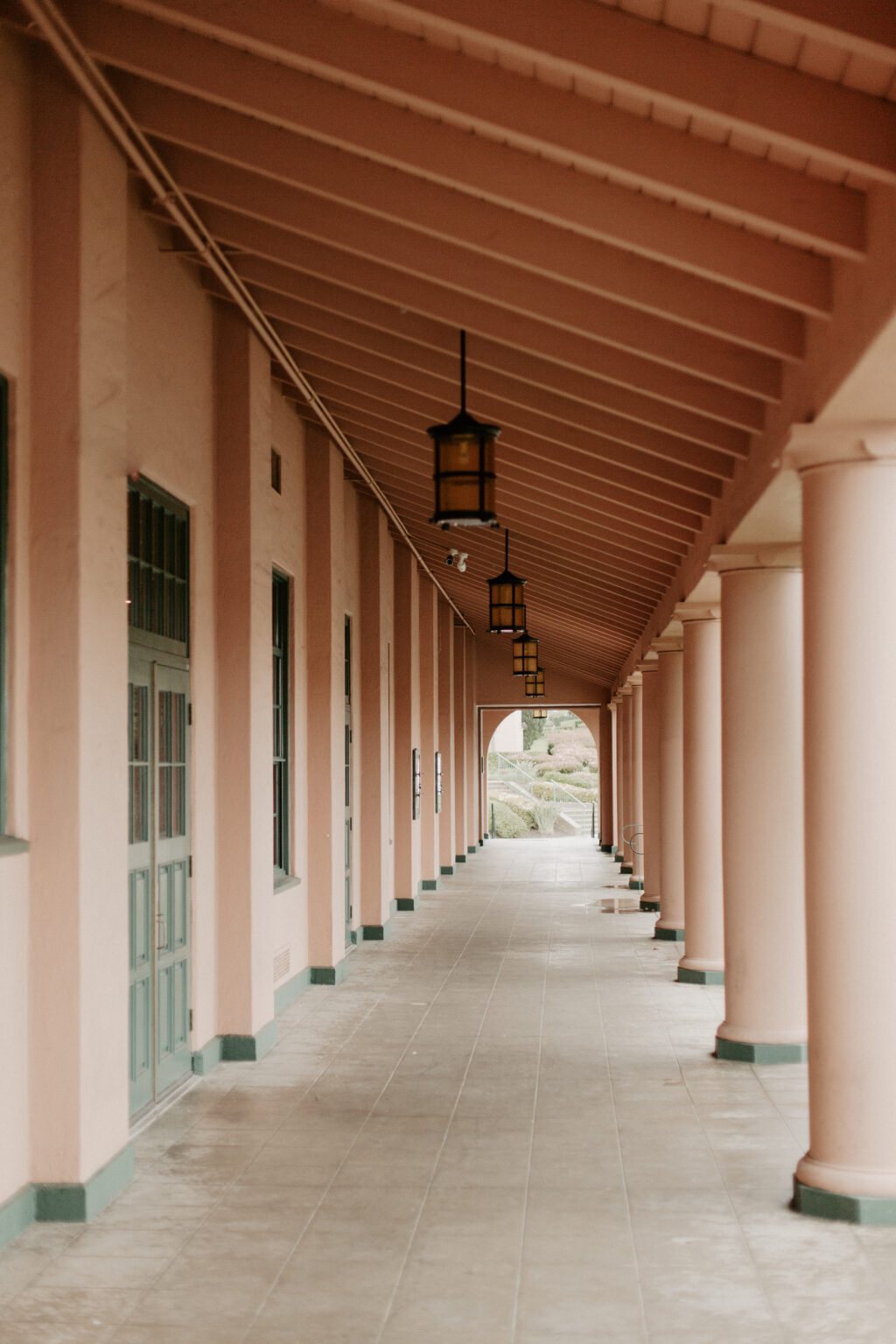 A covered colonnade walkway with arched openings and hanging lanterns
